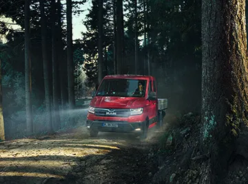 MAN TGE Pritschenwagen in Rot auf einem Waldweg